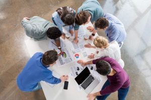 Deposit Foto: Gruppe junger Menschen arbeiten stehend an einem Tisch im Büro