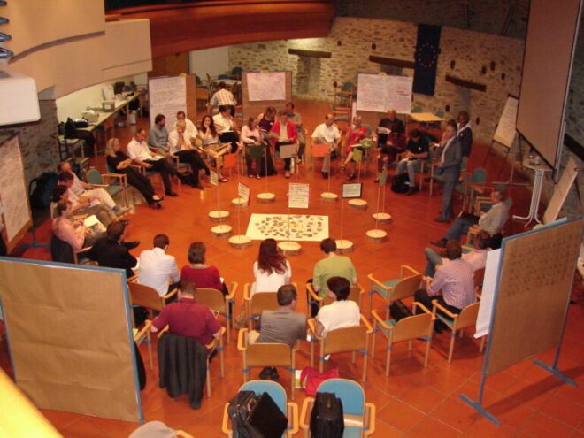 Workshop- Klausur-Setting: Dialogformat mit Sesselkreis, kreativ gestaltete Raummitte und zahlreiche PIN-Wände. Zukunftsklausur.